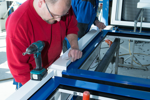  Mitarbeiter von Klein Metallbau in Kempenich setzen das Lüftungssystem Endura Twist auf einen Alu-Fensterrahmen in der Werkstatt. 