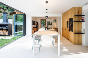  Zusammengefaltet und als Glaspaket auf der Terrasse geparkt, öffnet die Glas‑Faltwand den Innenraum vollständig zur Landschaft.  