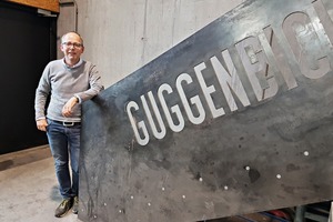  Otto Guggenbichler lehnt am Geländer einer himmelsleiterartigen Treppe, die die Werkshalle mit dem OG verbindet. 