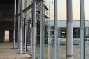  Pfosten-Riegel-Fassade auf einer Baustelle mit Bauanschlüssen am Fundament sowie an der Stahl­konstruktion 